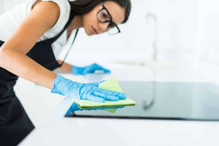 donna che svolge pulizia di cucina nella casa vacanze